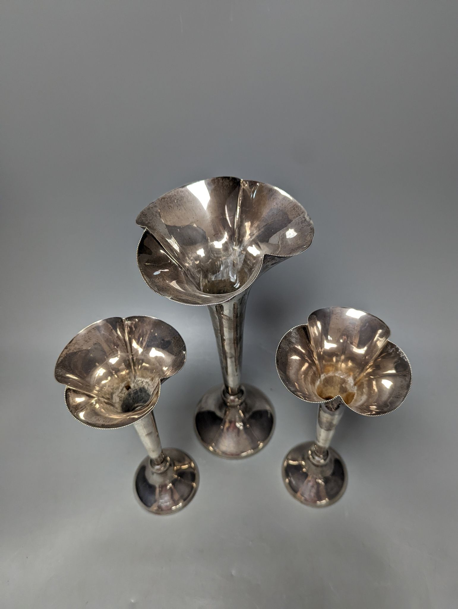A large George V silver mounted trumpet vase, 34cm and a pair of smaller silver mounted vases.